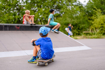 Boy sitting watching his friends at the skate park