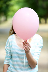 Girl holding balloon near face