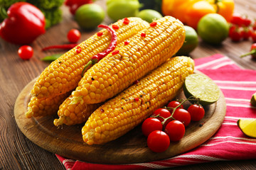 Fototapeta na wymiar Grilled corn served with vegetables on rustic round plate