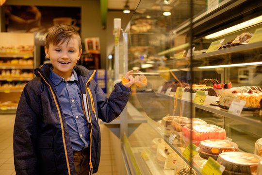 Little boy near display with cakes in a grocery store