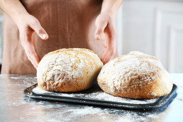 Baker checking freshly baked bread in kitchen of bakery