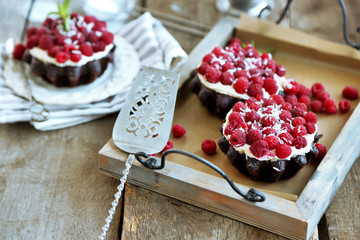 Sweet cakes with raspberries on wooden table background