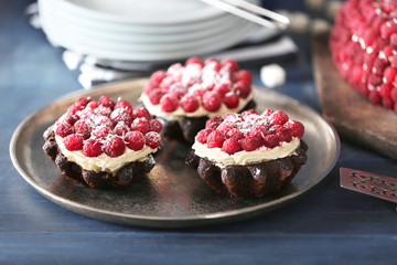 Sweet cakes with raspberries on color wooden background