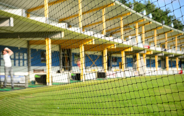 Golf driving range with golfer through protective net. Selective focus on net.