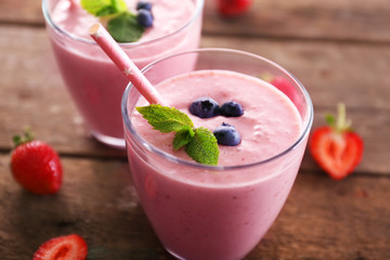 Fresh strawberry yogurt with berries around on wooden background