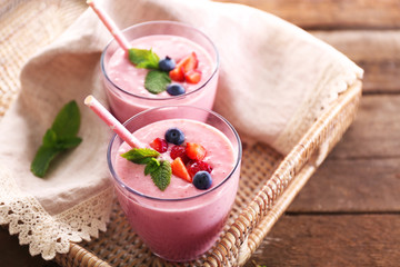 Fresh strawberry yogurt on wicker tray on wooden background
