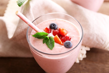Fresh strawberry yogurt and serviette against wooden background, close up
