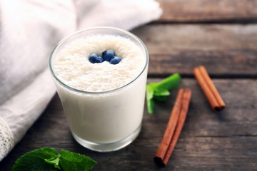 Fresh yogurt decorated with blueberries and cinnamon against wooden background
