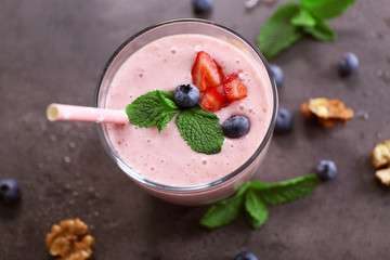 Tasty yogurt decorated with berries, nuts and mint on grey background, close up