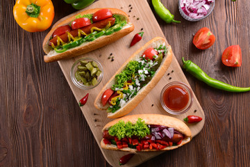 Hot dogs and vegetables on wooden cutting board