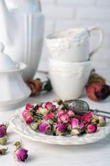 Obraz na płótnie Canvas Tea set and tea rose flowers on table on brick wall background