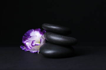 Obraz na płótnie Canvas Balanced pebbles with beautiful flower on dark grey background