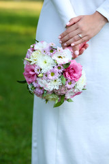 Obraz na płótnie Canvas Beautiful wedding bouquet in hands of bride on nature background