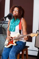 Female Singer With Eyes Closed Playing Guitar In Studio