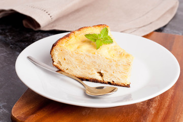 piece of cottage cheese pie with mint on a plate, closeup