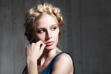 Portrait of a young woman with blonde hair in a cement background