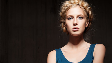 Serious woman with blonde hair on a dark background