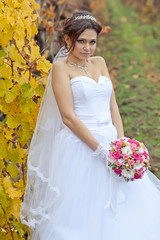 Fototapeta na wymiar Beautiful bride in autumn forest with bouquet 