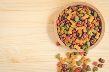 Dry dog food in wooden dish and wooden background