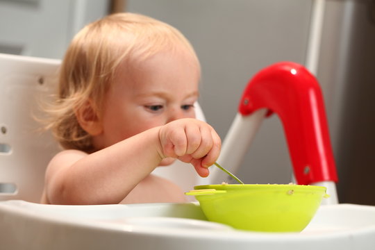 baby eats with a spoon from a plate
