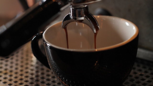 Espresso Maker Brew Tilt Close Up. camera tilts down on a macro shot of an espresso being brewed.
