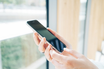 Girl holding smart phone in a hand on the blured background.