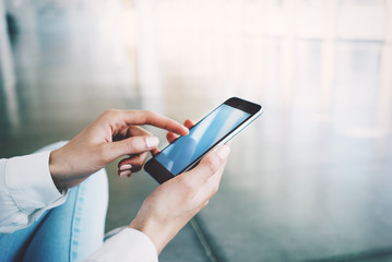 Smartphone holding in womans hand on the blured background.