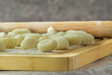 Fototapeta na wymiar Gnocchi di patate fatti a mano, su tagliere con mattarello, gnocchi di patate su farina