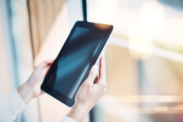 Blank tablet holding in woman hands on the blured background.