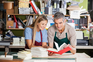 Smiling Workers Analyzing Notebook In Factory