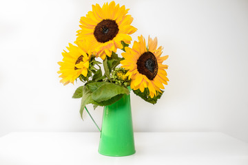 Bouquet of sunflowers in green vase on wooden table