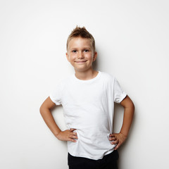 Smiling boy wearing white tshirt and shorts on the blank wall