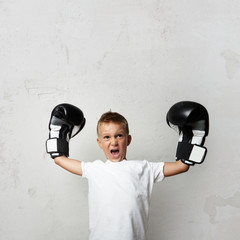 Little cute boy with boxing gloves celebrating his victory