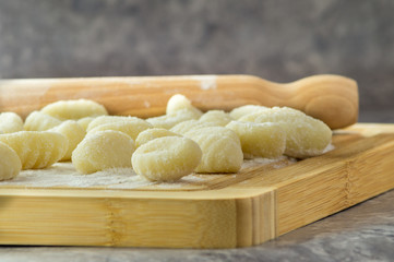 Gnocchi di patate fatti a mano, su tagliere con mattarello, gnocchi di patate su farina