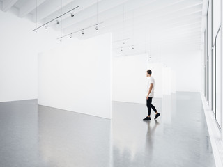 Gallery interior with white canvas and young man. 