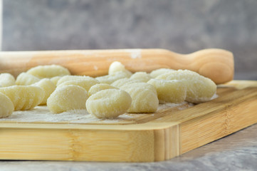 Gnocchi di patate fatti a mano, su tagliere con mattarello, gnocchi di patate su farina