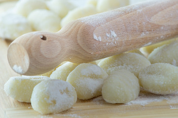 Fototapeta na wymiar Gnocchi di patate fatti a mano, su tagliere con mattarello, gnocchi di patate su farina
