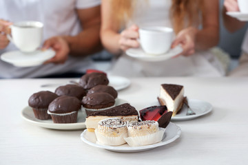 Friends hands with desserts and cups of tea, close up