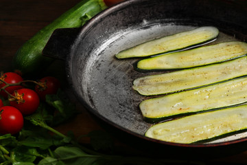 Fresh ingredients and fried zucchini slices for preparing zucchini rolls on wooden background