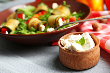 Salad with arugula and zucchini rolls on plate, on table background