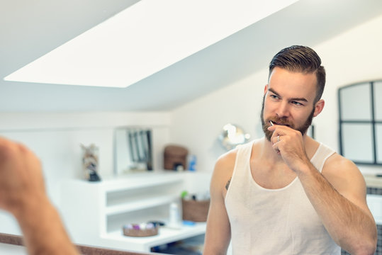 Mann mit Bart putzt seine Zähne