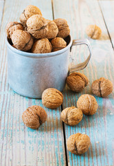 Pile of walnuts  a metal mug  on wooden background