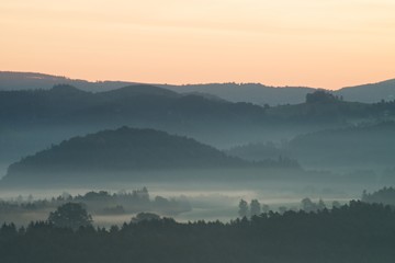 Blue morning. Hills and forests  lines in mountain valley during autumn sunset. Natural mountain landscape in cold mist