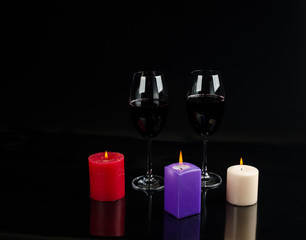 glass of wine and a candle on a black background