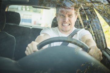 Wütender junger Mann sitzt im Auto