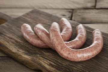 Rohe Bratwürstchen auf edlem Holzbrett
