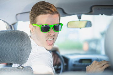Junger Mann mit Sonnenbrille sitzt im Auto