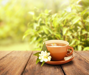 Cup of tea on wooden table, on nature background