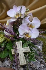Kleines Kreuz auf Trauergesteck mit Orchideenblüten