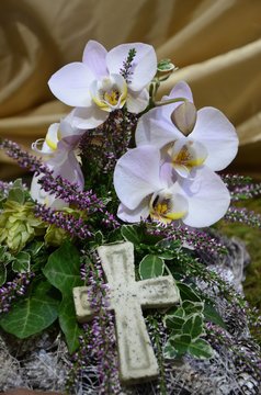Kleines Kreuz auf Trauergesteck mit Orchideenbl&uuml;ten